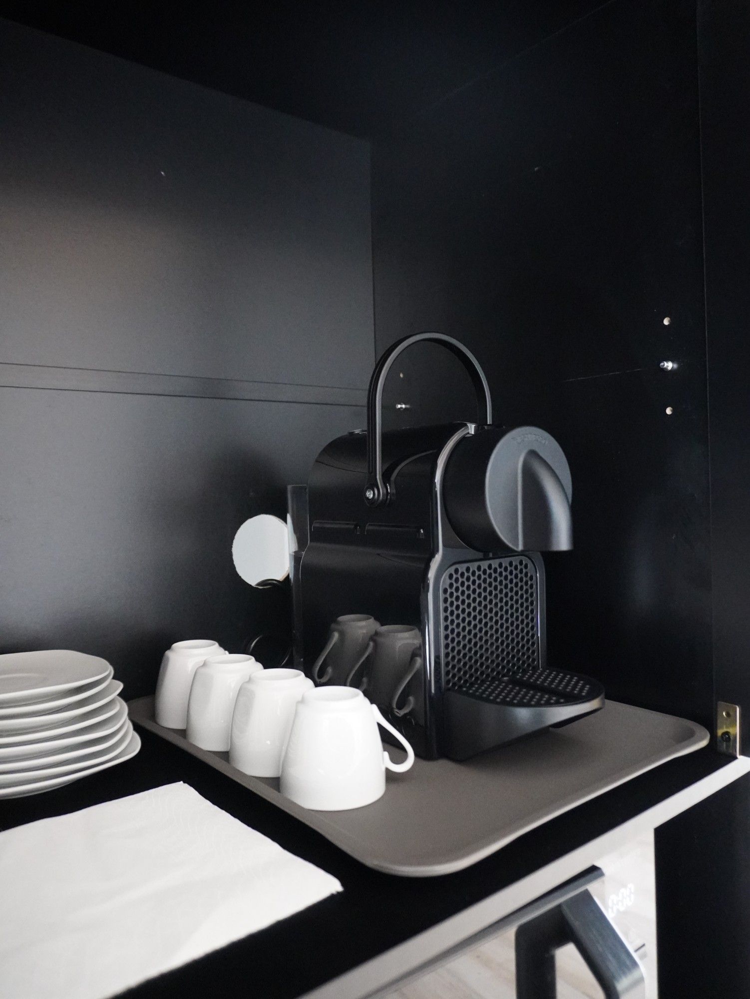 Espressomaschine im Küchenschrank des Apartments, davor Espressotassen und Teller