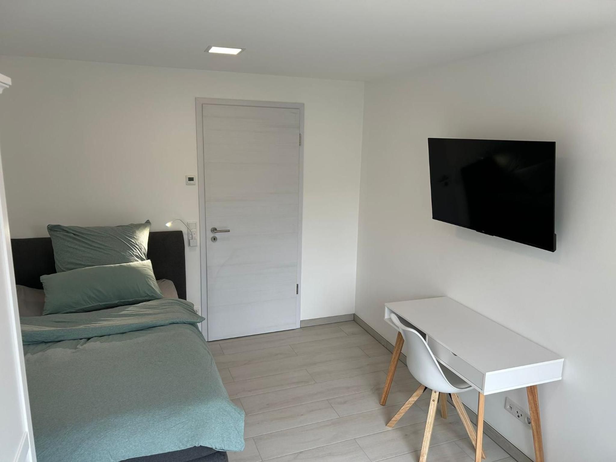 Einzelzimmer mit Boxspringbett, Schreibtisch und Fernseher