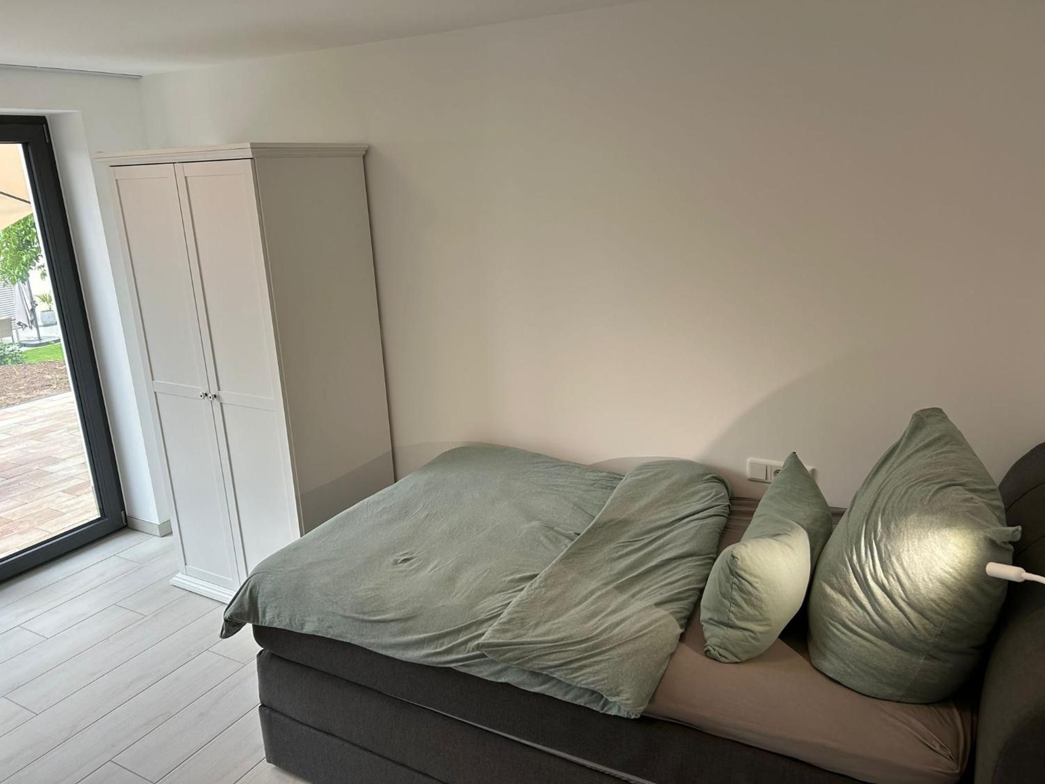 Einzelzimmer: Boxspringbett mit Leselampe, links Kleiderschrank und Terrassentür
