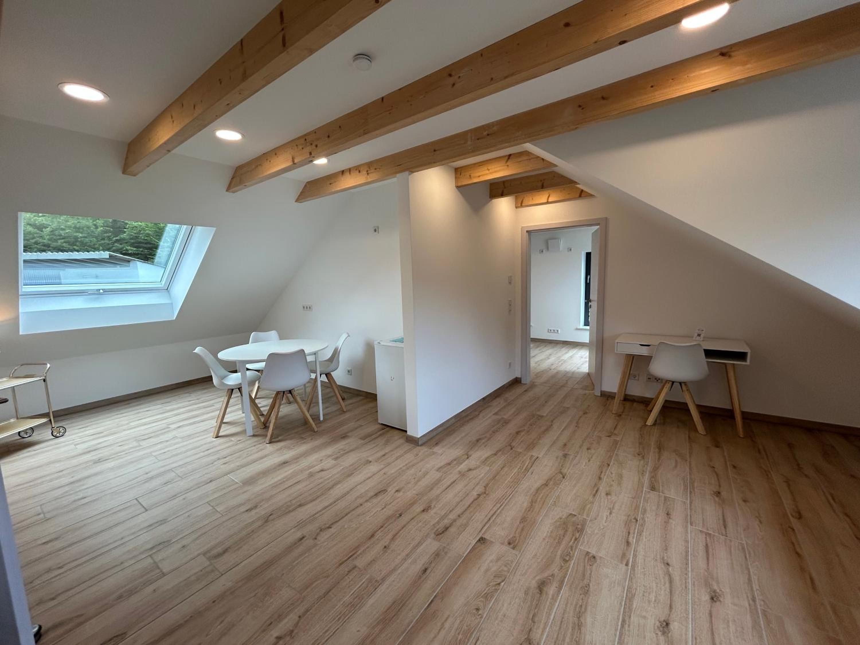Wohn- und Essbereich im Apartment mit Dachfenster, rundem Esstisch und Schreibtisch