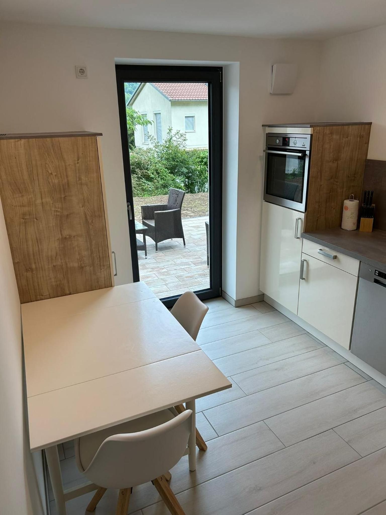 Küche: Esstisch mit zwei Stühlen, Backofen und Glastür zur Terrasse
