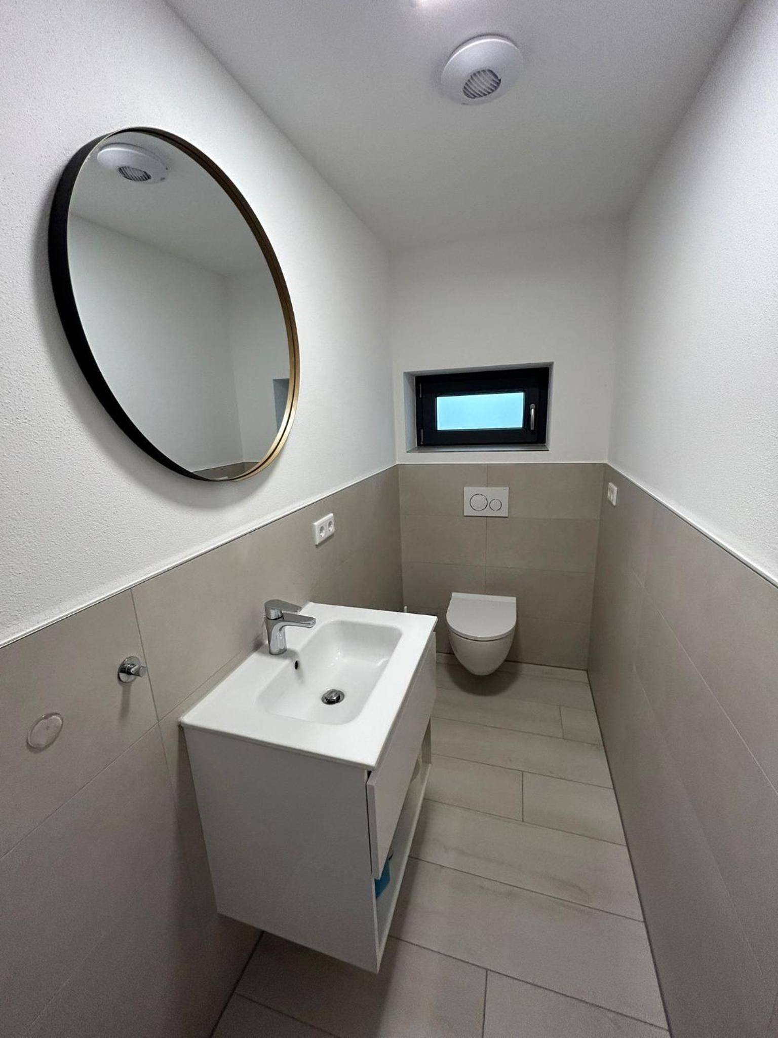 Separates WC mit Waschbecken und rundem Spiegel