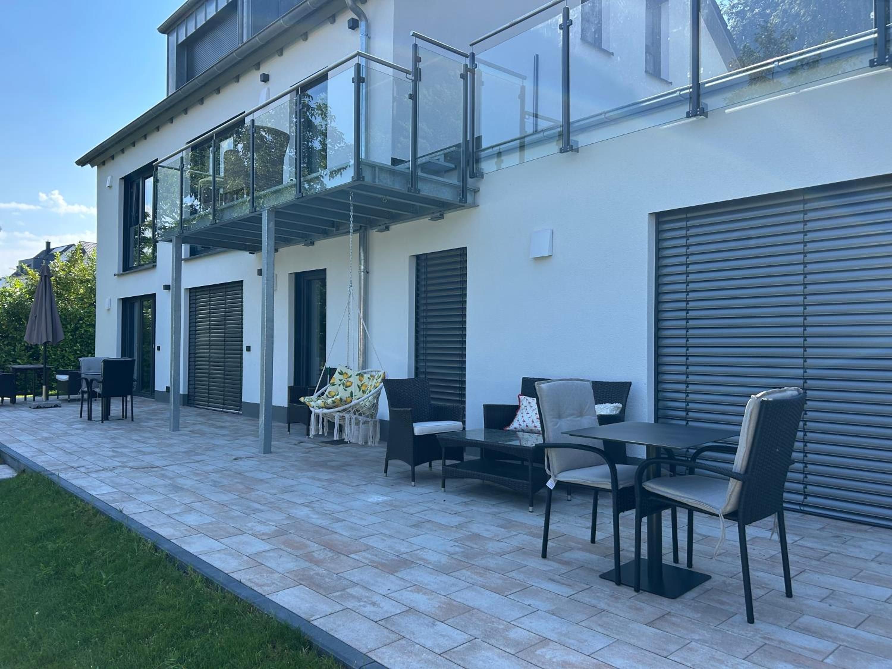 Terrasse vor dem Haus mit Sitzgruppen, Hängesessel und Tischen in der Sonne