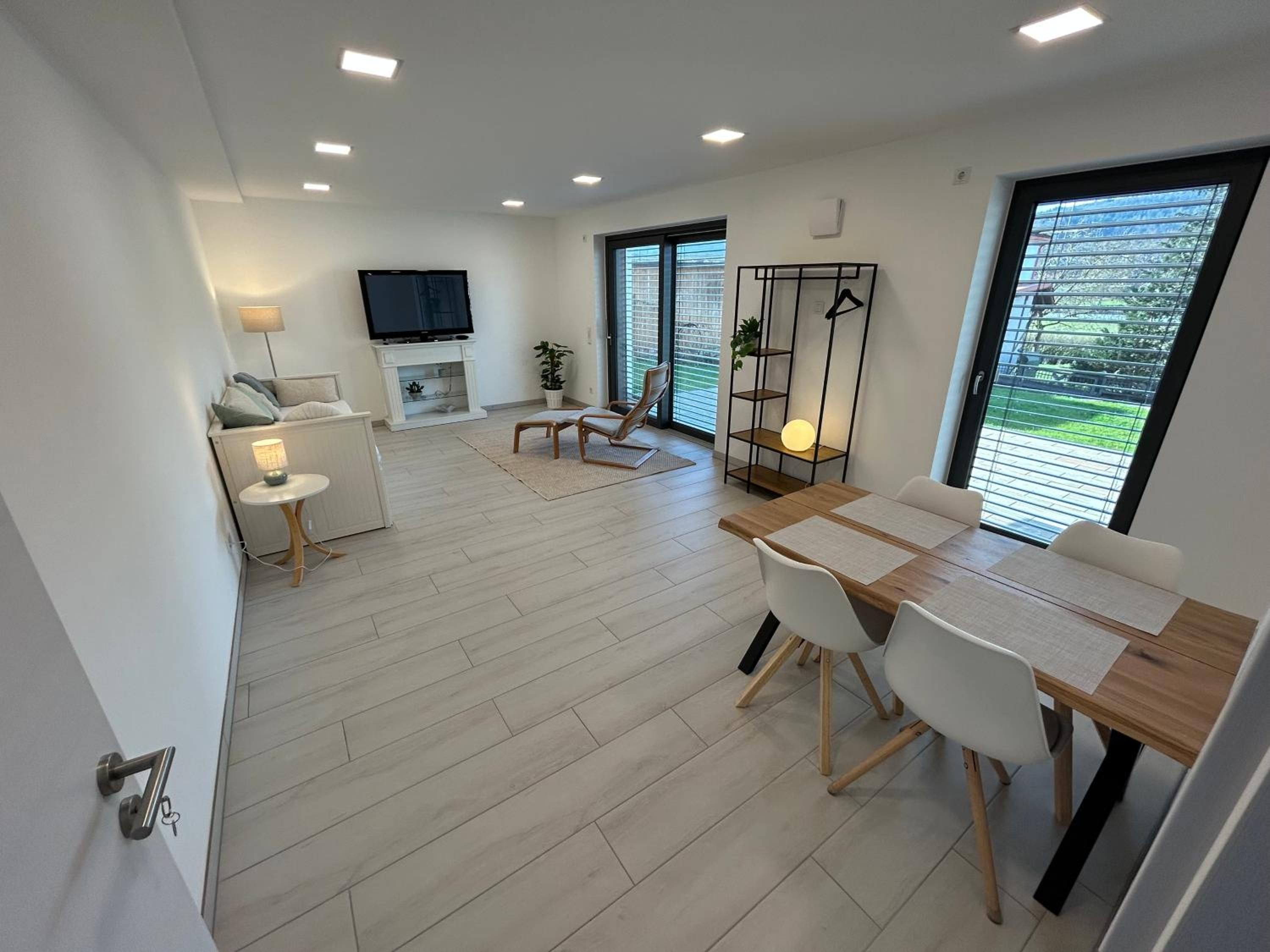 Wohnzimmer der Ferienwohnung mit Esstisch für vier, Tagesbett, Fernseher und Relaxsessel